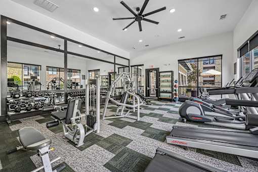 A gym with a variety of equipment including treadmills, weights, and exercise machines.