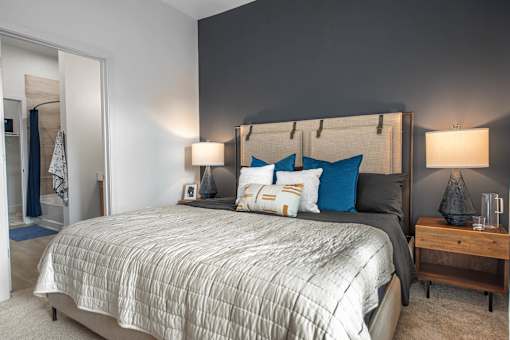 A bedroom with a large bed and a wooden nightstand.
