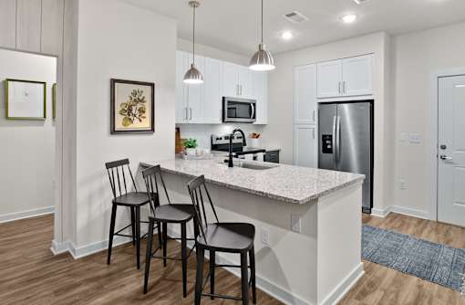 A kitchen with a white countertop and black barstools.