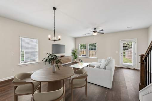 A living room with a white couch, a round table, and a chandelier.