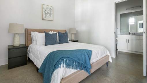 A bedroom with a bed, two lamps, and a framed picture on the wall.