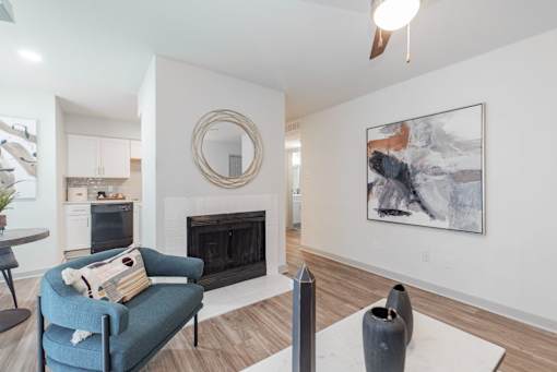 A living room with a fireplace, a blue chair, and a painting on the wall.