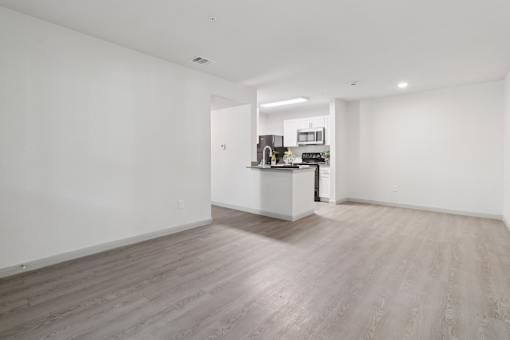 A spacious room with a kitchen area in the background.