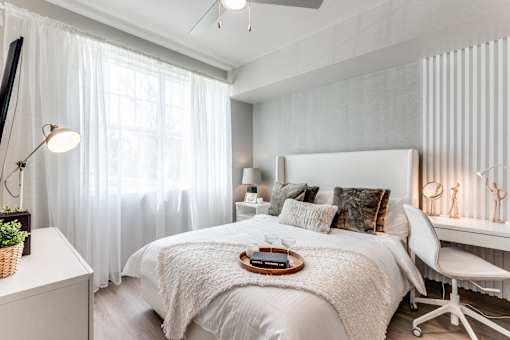 A bedroom with a large bed and a window with curtains.