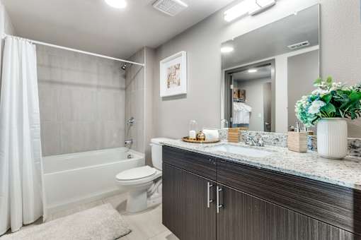 A modern bathroom with a white toilet, a white shower curtain, and a white rug.