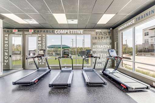 Three treadmills are lined up in a row in a gym.