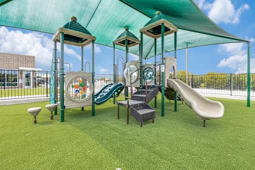 A playground with a green slide and a green canopy.