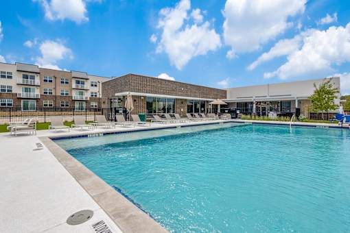 A large swimming pool in front of a building with a sunny sky.