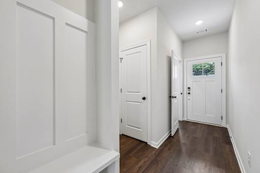 A white hallway with a bench and a door.