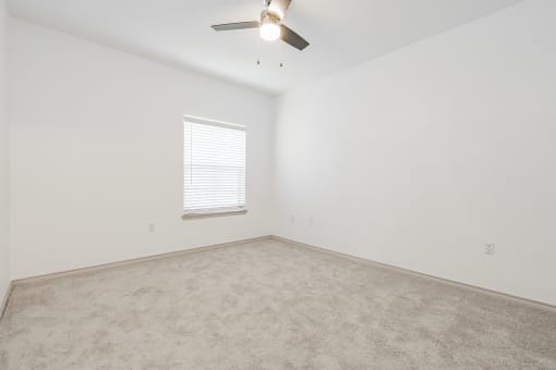 an empty room with a ceiling fan and a window