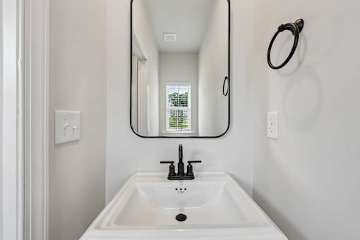 A white sink in a bathroom with a round mirror above it.