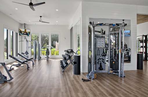 A spacious gym with a variety of equipment and a ceiling fan.