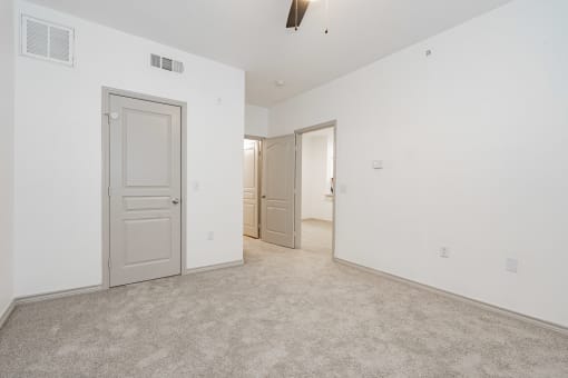 a bedroom with white walls and carpet and a door to a closet