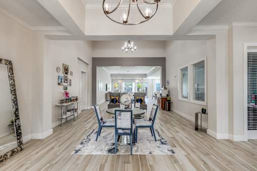 A dining room with a table set for four and a chandelier hanging from the ceiling.