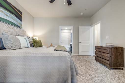A bedroom with a large bed and a wooden dresser.