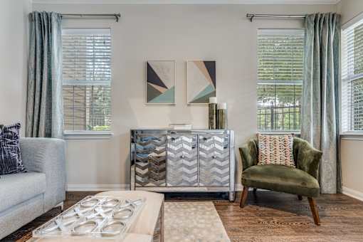 A living room with a grey couch, a green chair, and a patterned artwork on the wall.