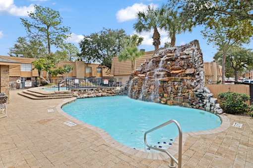 A pool with a waterfall and a slide.