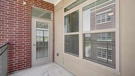 A white door with a window above it and a brick wall to the left.