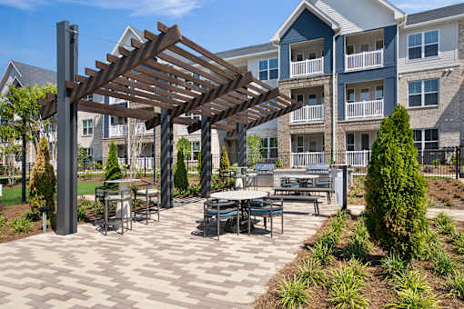 A patio with a table and chairs under a wooden pergola.
