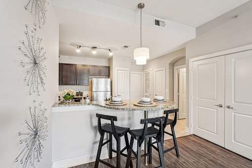A modern kitchen with a dining table set for two.