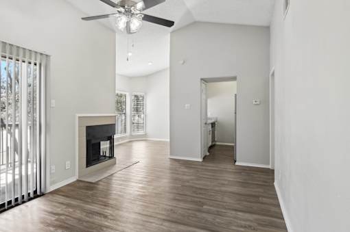 A spacious living room with a fireplace and a ceiling fan.