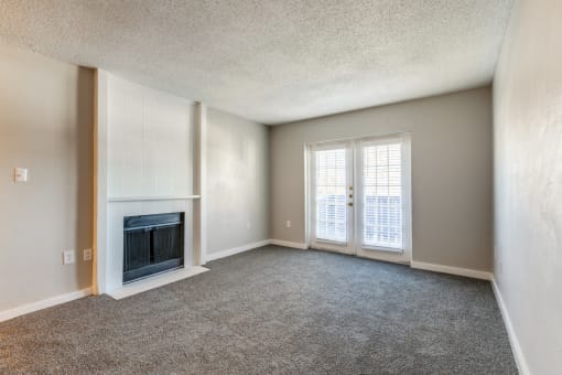 an empty living room with a fireplace and windows