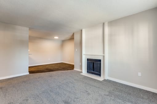 an empty living room with a fireplace and a carpeted floor