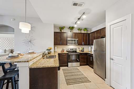 A kitchen with a refrigerator, sink, and oven.