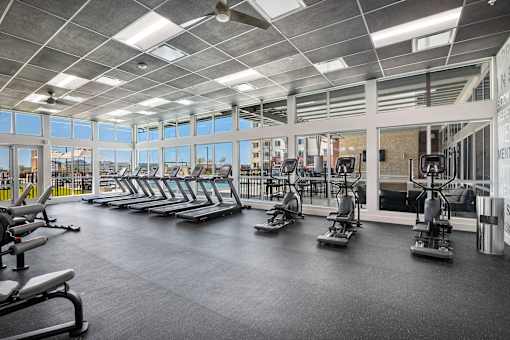 A gym with treadmills, elliptical machines, and a fan.