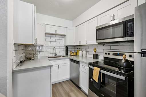 A modern kitchen with white cabinets and stainless steel appliances.