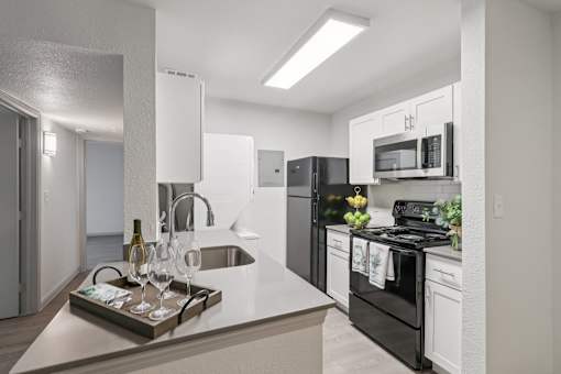 A modern kitchen with black appliances and white cabinets.