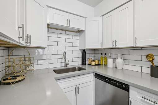 A kitchen with white cabinets and a stainless steel dishwasher.
