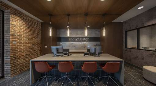 A conference room with a long table and chairs, a computer, and a sign that reads "The Register.".