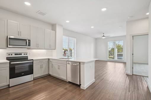 A kitchen with white cabinets and a wooden floor.