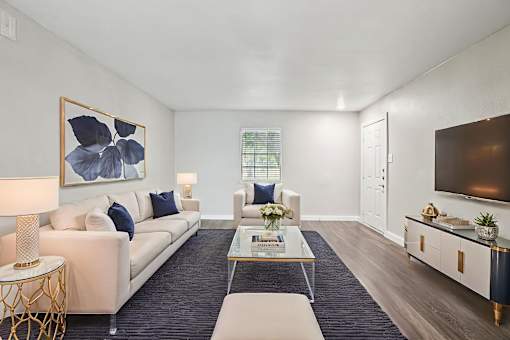 A living room with a white sofa, a coffee table, and a painting on the wall.