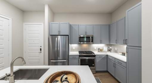A modern kitchen with a white countertop and grey cabinets.