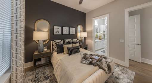 A bedroom with a bed, two lamps, and a mirror on the wall.