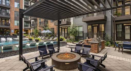 A patio with a fire pit and chairs.