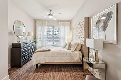 A bedroom with a bed, dresser, and a ceiling fan.