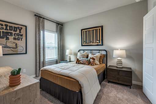 A bedroom with a bed, nightstand, and a poster on the wall.