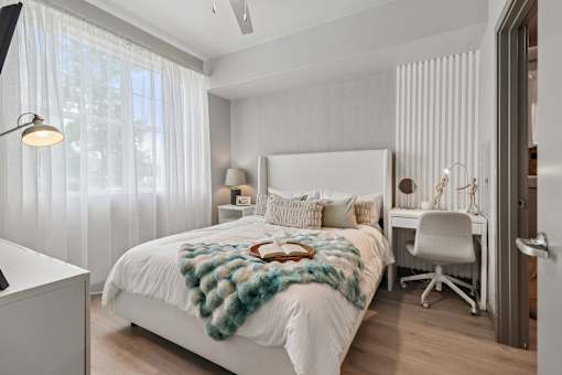 A bedroom with a white bed and a white chair.