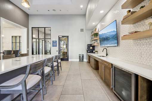A modern kitchen with a long counter and chairs.