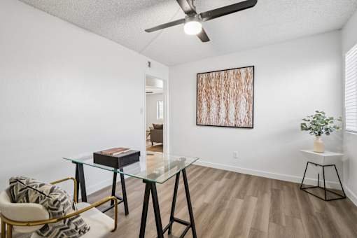 A room with a glass table and a painting on the wall.