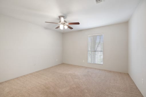 the living room of an empty home with a ceiling fan