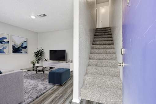 A living room with a grey couch and a television on the wall.