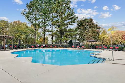 A large swimming pool surrounded by trees and a fence.