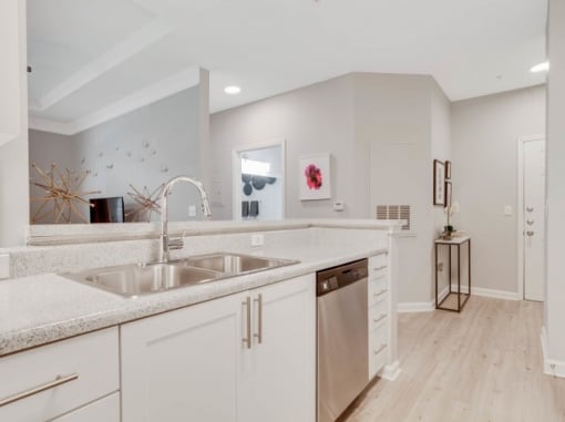 a large kitchen with white cabinets and a stainless steel sink