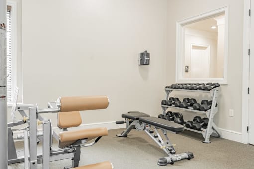 the gym with weights and chairs at the grove apartments