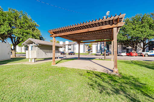 A wooden pergola stands over a grassy area.