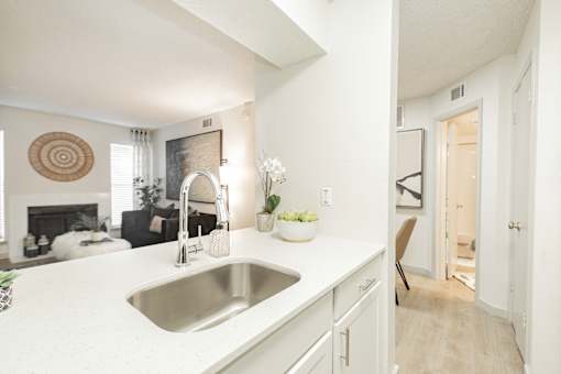 A kitchen with a white countertop and a stainless steel sink.
